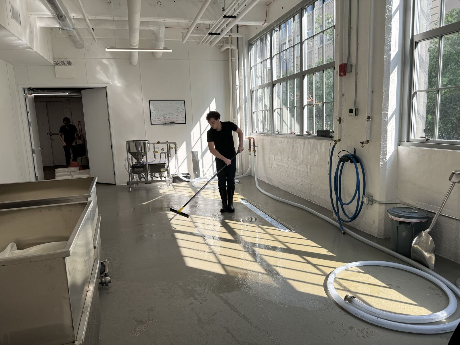 Washing down the brewery floor after rice steaming, sunlight through the factory windows