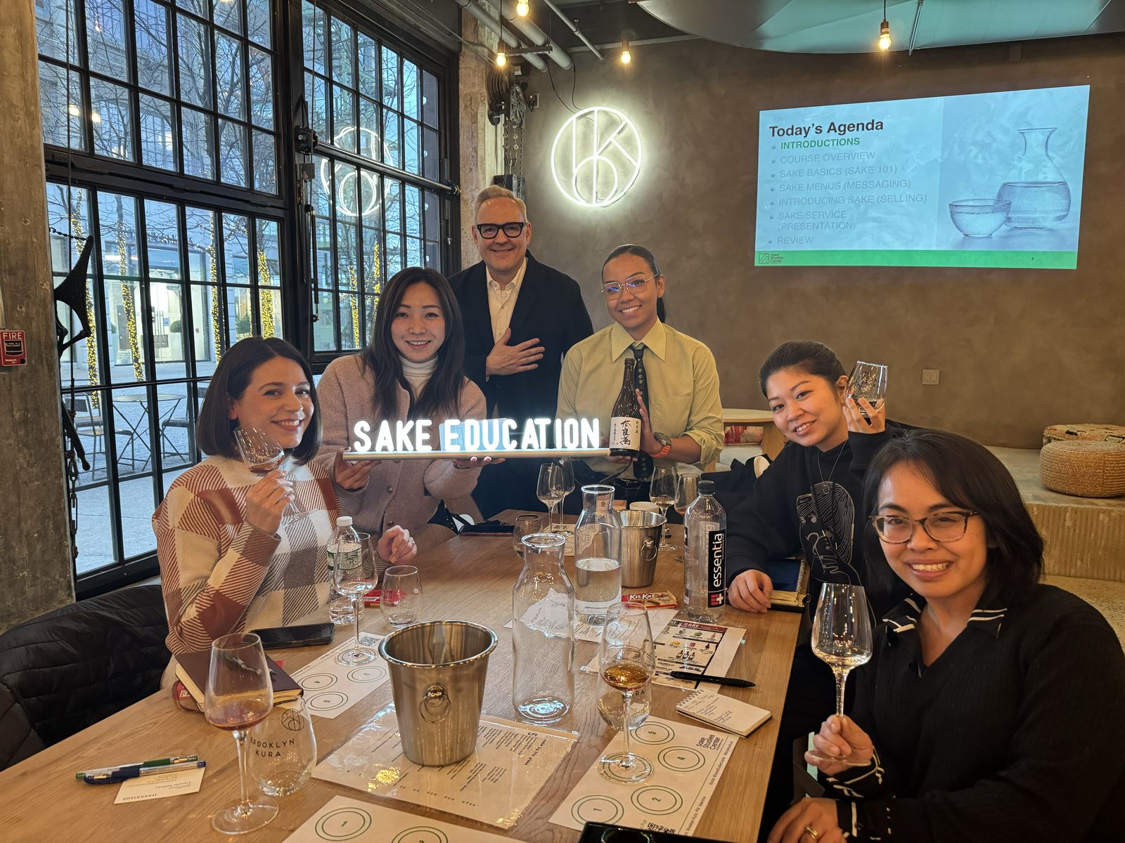 A Sake Server Certification class raising glasses with the Sake Education sign