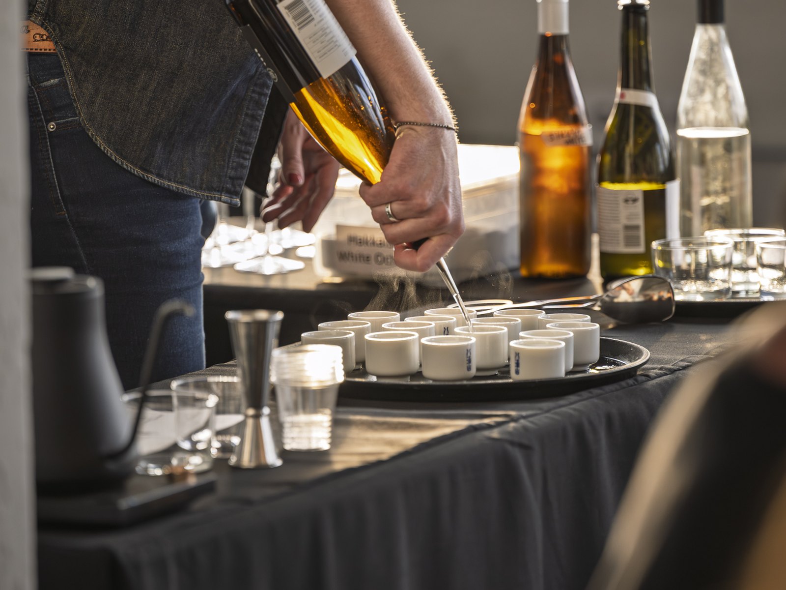 Pouring a shochu tasting flight into cups at the Sake Studies Center